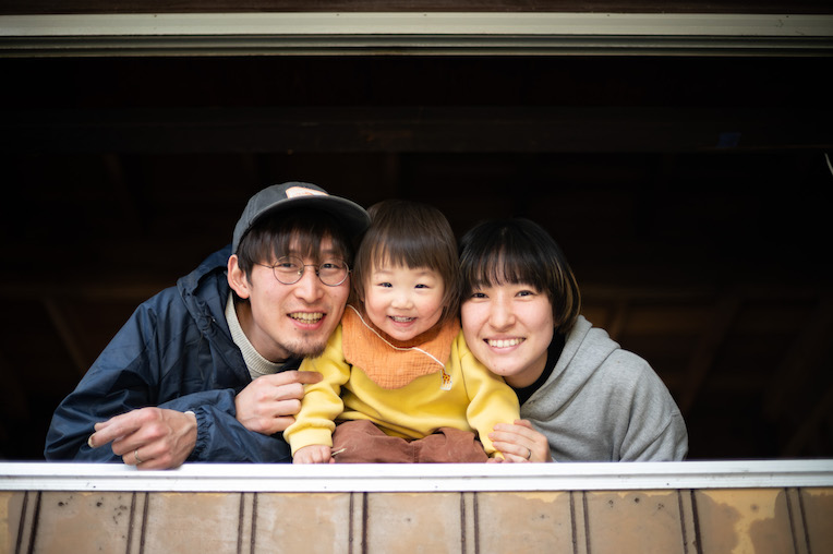 窓辺から顔をのぞかせる大木さん家族の3人
