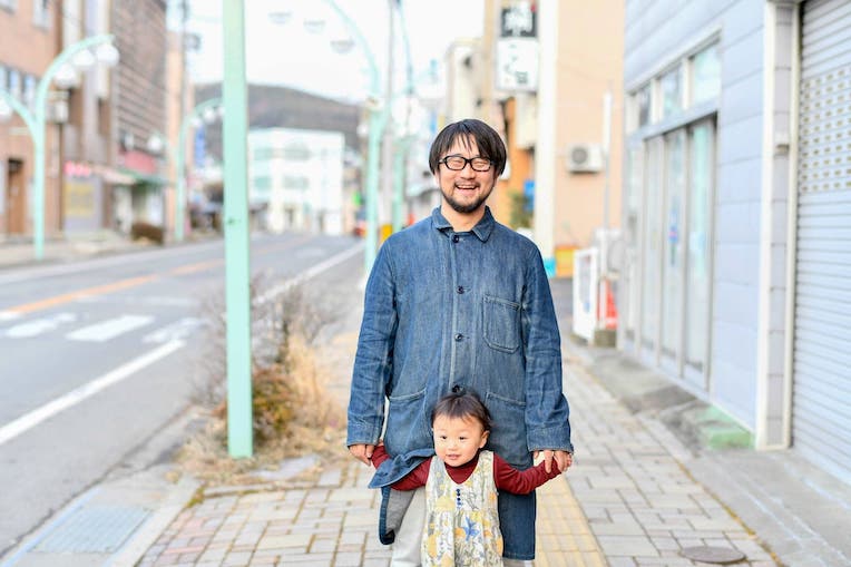商店街の通りで小さな子どもと並んで立つ赤羽孝太さん