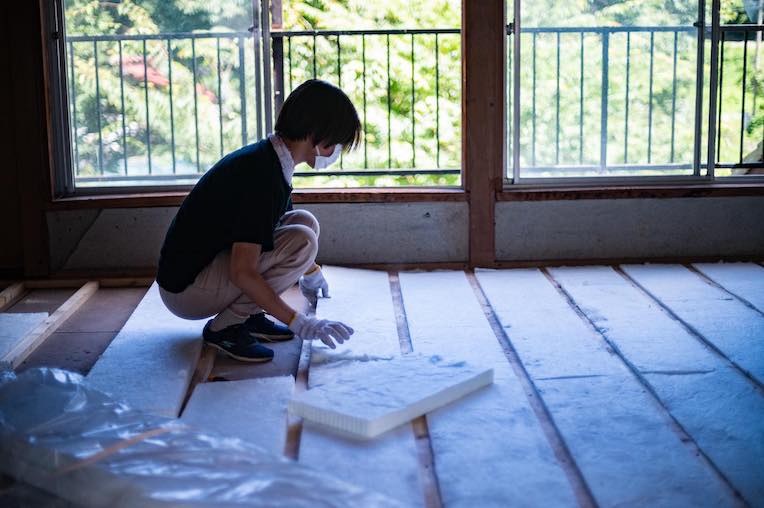 ガレージ2階の床にグラスウールの断熱材を敷く作業